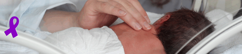 Bebê prematuro dentro de incubadora recebendo cuidado delicado de um profissional da saúde, representando a conscientização do Novembro Roxo sobre prematuridade.