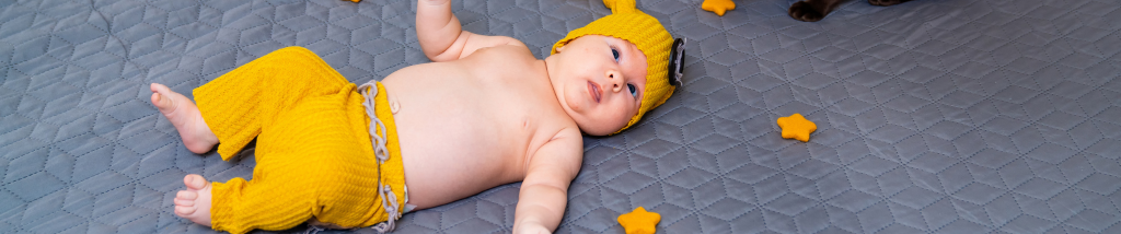 Bebê deitado sobre um tapete usando roupa amarela durante momento de descanso e desenvolvimento na primeira infância