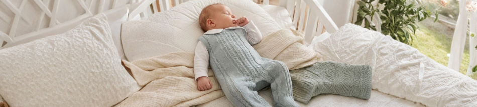 Bebê dormindo confortavelmente em berço usando roupa de inverno em tecido macio e respirável.