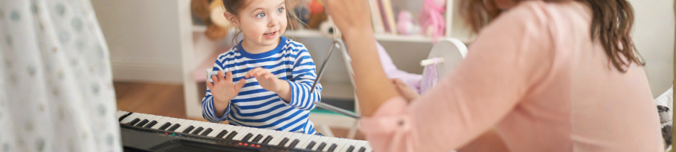 Criança participando de atividade de musicalização infantil com teclado e interação durante aula de música
